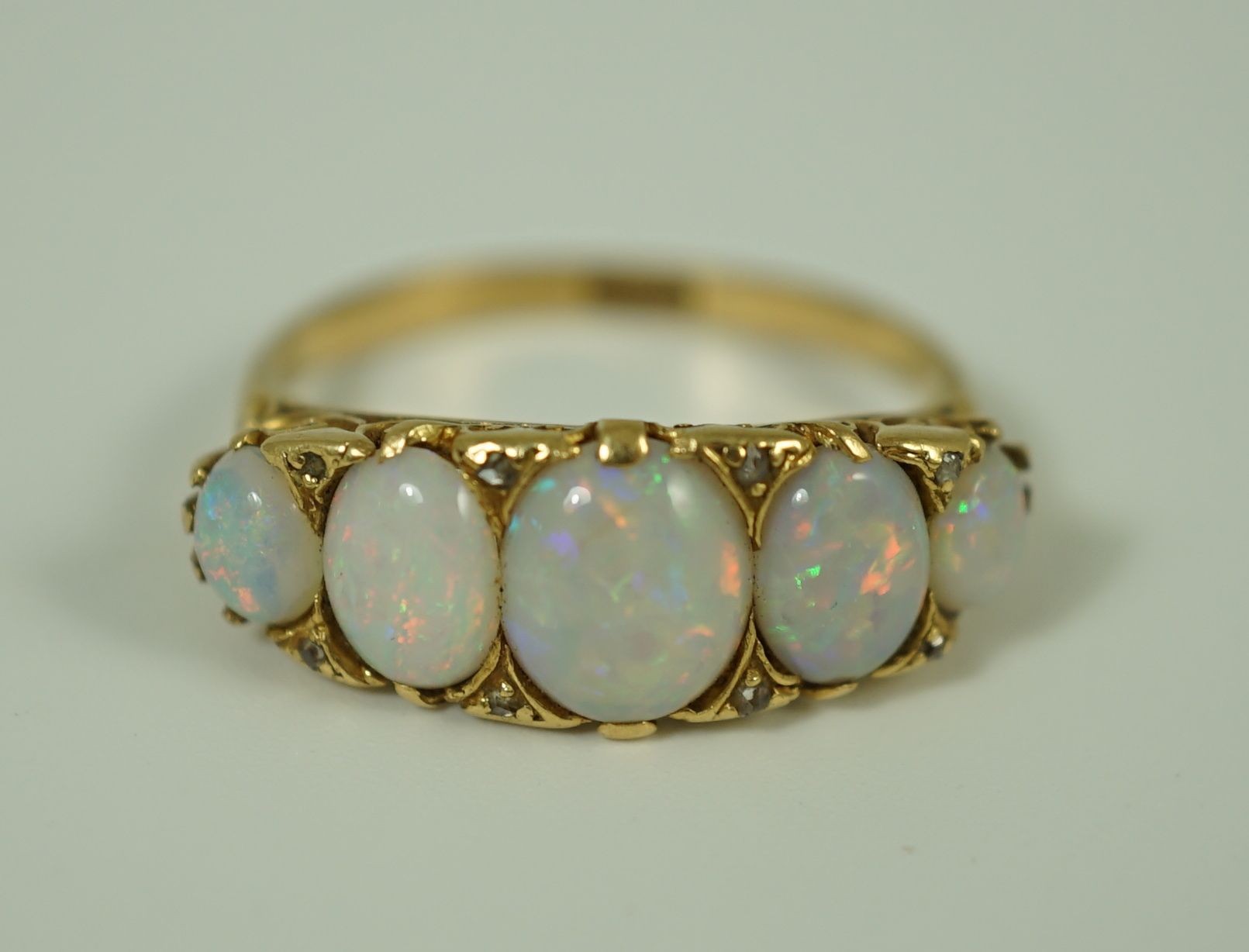 An 18ct gold and graduated five stone opal half hoop ring, with diamond chip spacers